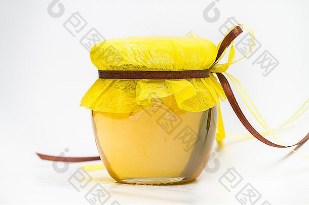 罐中的草药蜂蜜，带有小蜂巢和白色背景上分离的草药