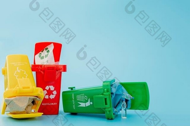 黄色、绿色和红色回收箱，蓝色背景上带有回收符号。保持城市整洁，留下回收标志。自然保护概念