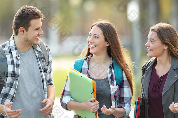 三名学生在大学校园内行走和交谈的正面视图