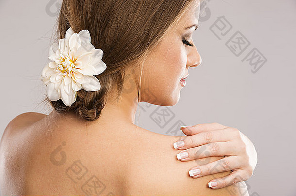 头发上插着白花的美女肖像。在灰色背景上隔离。