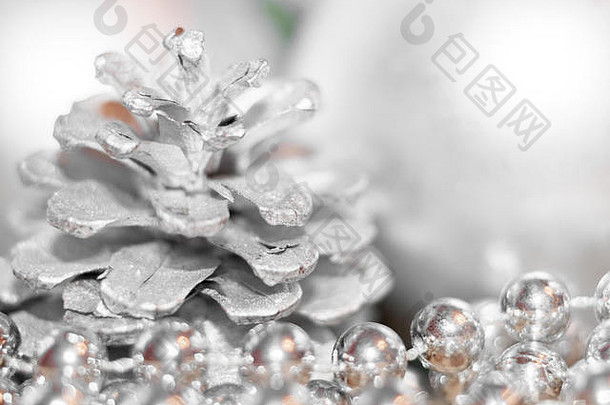 具有软焦点的抽象圣诞背景。银色松果和珠子的轮廓在前景中，模糊的球在背景中。