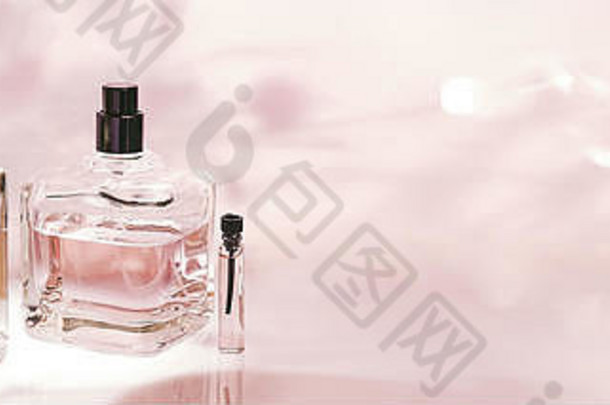粉红色花朵背景上的不同香水瓶和采样器。香水收藏、化妆品横幅