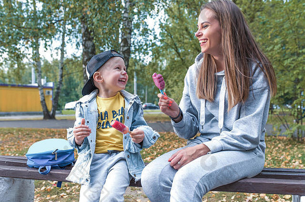 快乐家庭，坐在长椅上，妈妈带着4-5岁的小男孩，吃冰淇淋，支持关爱教育，小吃大自然，放松<strong>夏秋</strong>