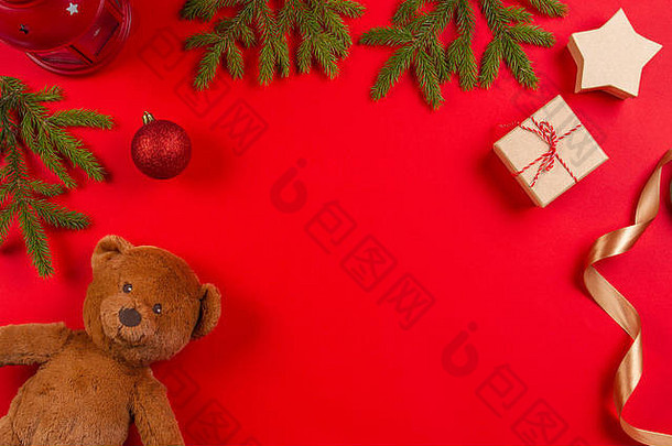 圣诞作文。红色背景上的泰迪熊、冷杉树枝、圣诞装饰品和礼品盒