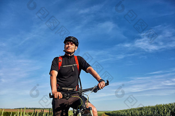 年轻的骑自行车的人和山地自行车的人在乡村的小路上迎着日出。