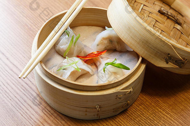 亚洲餐厅木桌上竹蒸笼里的虾仁点心