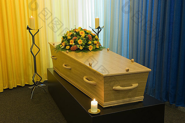 太平间里有两支燃烧着的蜡烛的有插花的棺材