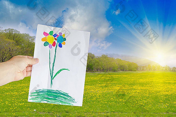 在黄色草地的背景上，一只手拿着一张花童的画