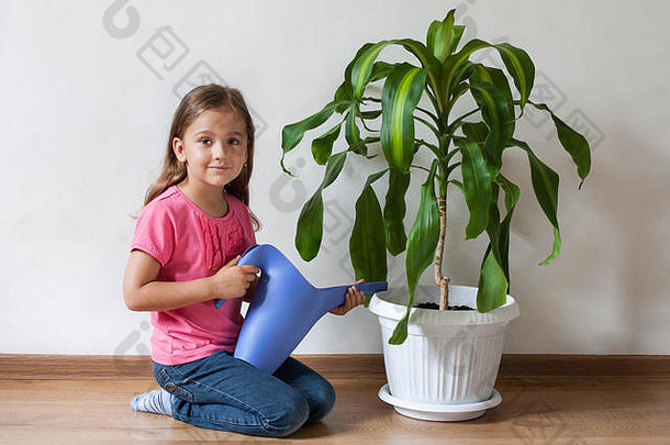 可爱的六年女孩孩子浇水浇水手植物棕榈蓝色的浇水室内护理植物