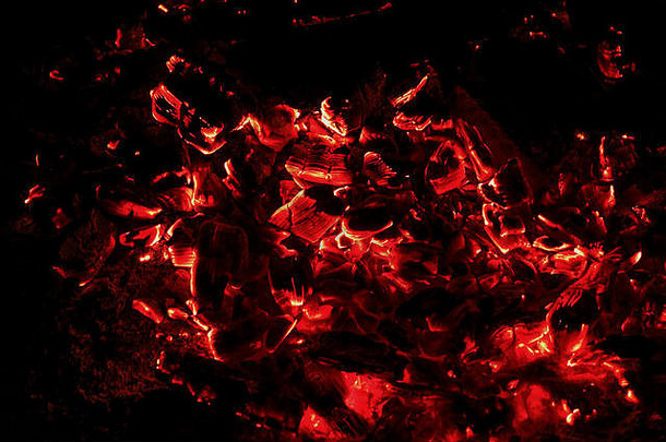 黑色和红色抽象背景：在黑色背景上的火中阴燃和燃烧煤炭