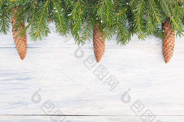 冷杉树枝有球果，白色木质背景上有雪花。圣诞节和新年概念