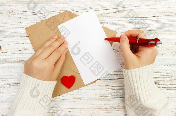 情人节写情书的女孩之手。手工制作的明信片。女人为2月14日的节日庆典写明信片。平铺。顶视图。