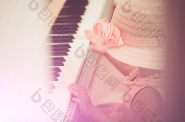 戴着复古粉色帽子、穿着连衣裙、戴着珠子项链的孩钢琴