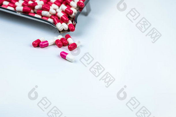 白色桌子上的粉白色和<strong>红</strong>白色胶囊以及模糊的<strong>不锈钢</strong>药盘。情人节情药的概念。制药工业