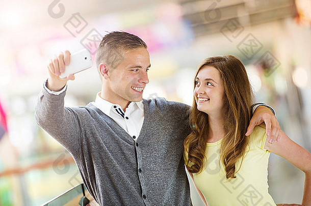 年轻的夫妇采取自拍手机购物购物中心