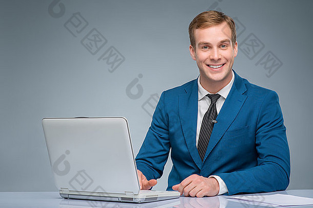 面带微笑的<strong>新闻</strong>记者正在用他的笔记本电脑工作。