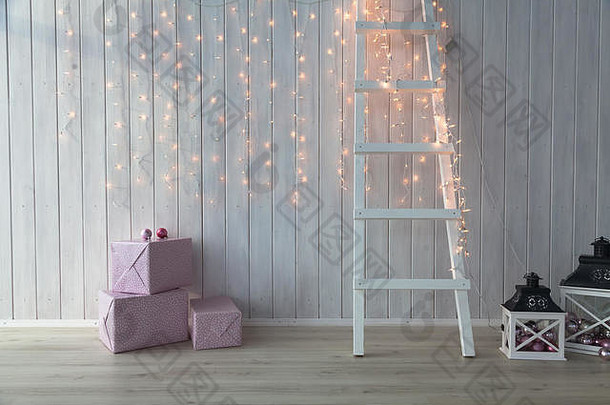 在白色木质背景上点燃的圣诞灯，还<strong>有</strong>粉红色的礼品盒和楼梯