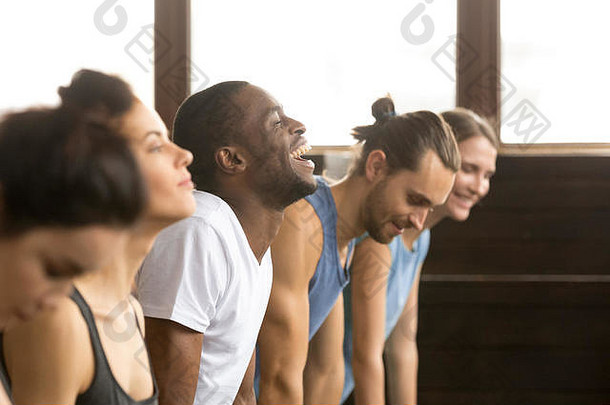 非洲男子在集体训练时笑着做瑜伽或木板