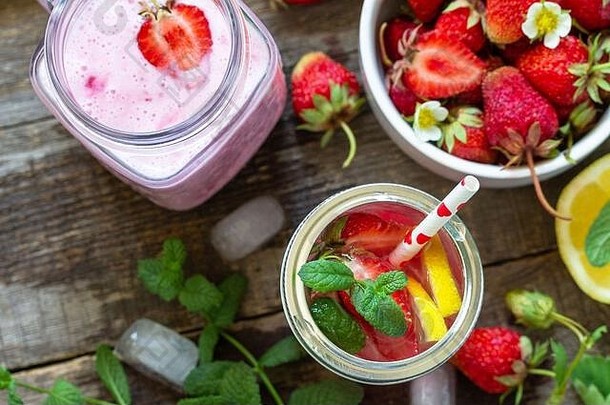健康饮食观念。柠檬水配新鲜草莓和草莓水果酸奶冰沙或牛奶奶昔，放在乡村木桌上。俯视平面图l