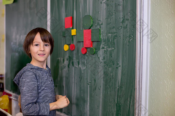 <strong>一年级</strong>的孩子，在学校学习<strong>数学</strong>，形状和颜色，站在黑板前