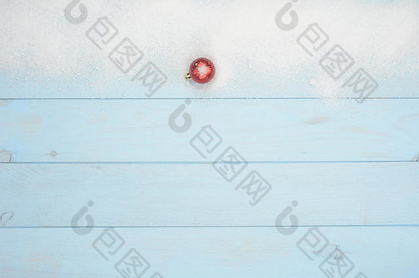 蓝色木头上有雪和一个红色球的圣诞明信片