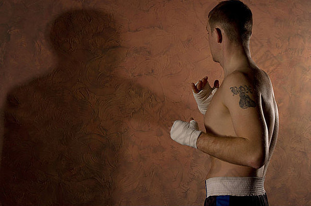拳击手纹身工作健身房缠着绷带的拳头铸造影子黑暗棕色（的）阴暗的墙Copyspace