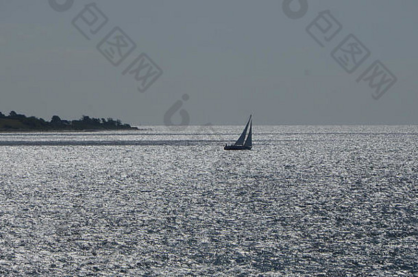 帆船出现轮廓离开土地闪亮的水表面小涟漪反映阳光