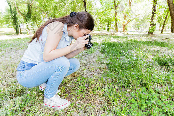 年轻的女人使图片植物古董相机女业余摄影师采取照片自然