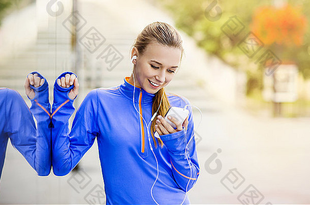 在市中心跑步时，年轻的女跑步者正在休息和听音乐