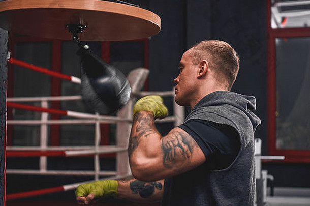 硬臂训练。在拳击馆里，肌肉发达的年轻运动员用拳击速度袋训练他的协调能力