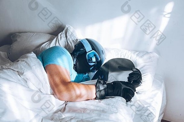躺在床上的男人，戴着滑雪板滑雪镜和头盔