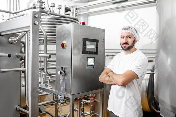 在奶酪或牛奶厂使用控制面板操作巴氏杀菌机的工人
