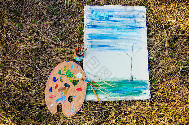 在草地背景上使用颜料和画笔的图片和艺术家调色板