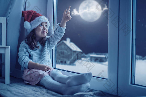 可爱的小女孩看着月亮和冬日的天空