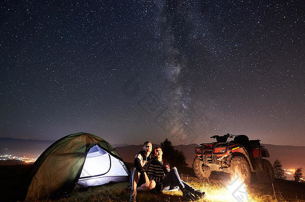 年轻的夫妇男人。女人三维勒坐着发光的旅游帐篷燃烧篝火亚视四摩托车前山享受美丽的视图晚上天空完整的星星乳白色的