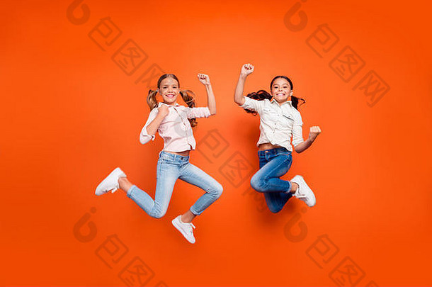 正面可爱的两个孩子的全长照片女孩跳跃庆祝学校比赛胜利举起拳头展示力量穿白色衬衫牛仔牛仔裤