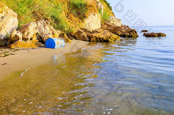 用于储存水和其他液体的蓝色塑料桶被海水冲到沙滩上，成为废物。