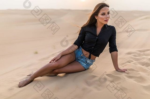 坐在沙丘上，坐在沙滩上的美丽年轻<strong>女</strong>子