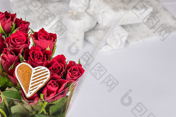 一束红玫瑰和甜心，祝你好运。背景为白色礼物的装饰花。庆祝、生日、周年纪念、情人节。