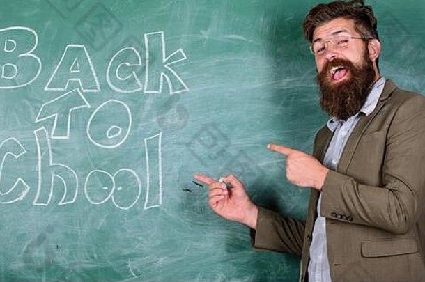 老师或教育家站在黑板旁欢迎学生返回学校。准备好教你了。放假后，老师开始上第一课。学校和学习观念。