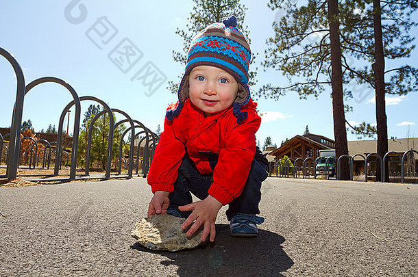 一个一岁的男孩在户外的公园里玩木屑和建筑，让他开心。