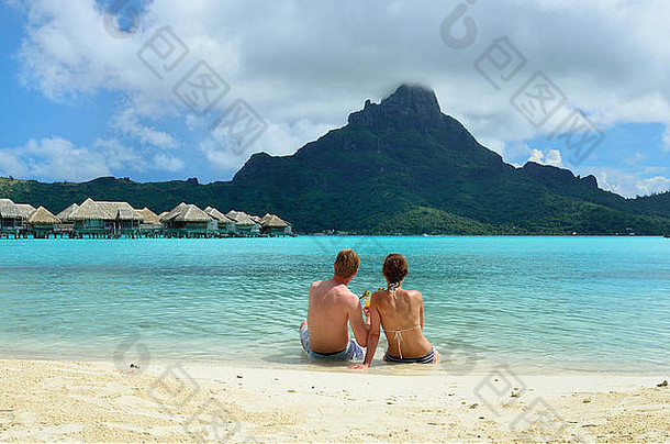 度蜜月夫妇喝鸡尾酒海滩奢侈品假期度假胜地环礁湖视图热带岛