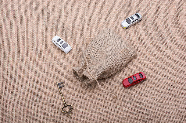 钥匙和玩具车放在亚麻帆布上的袋子周围