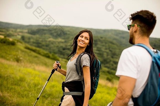 微笑年轻的夫妇走背包绿色山