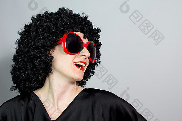 滑稽的红唇女人戴着黑色假发，戴着红色眼镜，摆出独立的空间背景