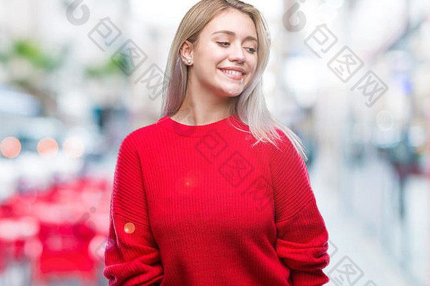 年轻的金发女郎穿着冬季毛衣，在孤立的背景下，面带微笑，表情自然。自信地笑。