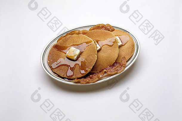 三个煎饼三个融化的黄油糖浆两个三点培根快餐丰盛早餐白色背景