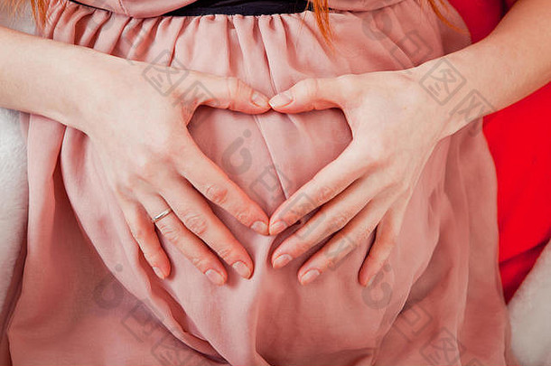 怀孕了女人持有手心形状婴儿撞怀孕了肚子手指心象征孕妇概念婴儿淋浴
