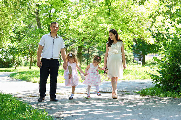 一家人带着孩子和孕妇在夏日城市公园散步