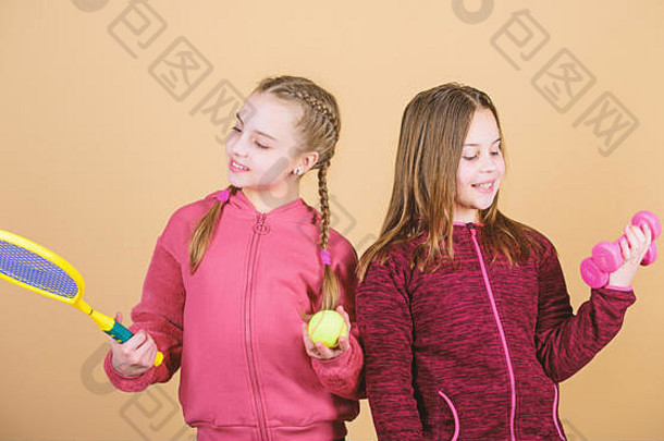朋友们准备好接受训练了。帮助孩子们找到他们喜欢的运动的方法。女孩们带着运动器材哑铃和网球拍，可爱的孩子们。我们热爱运动。这孩子可能在完全不同的运动中表现出色。